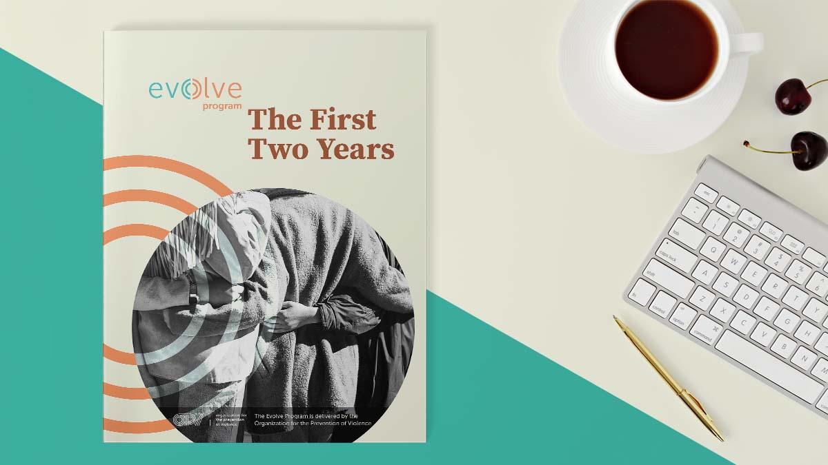 Evolve Program: The First Two Years report sitting on a desktop surface near a cup of coffe